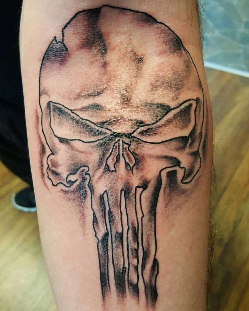 Punisher Skull tattoo on the leg with a faded, worn appearance, featuring soft shading and detailed line work for a distressed yet bold look