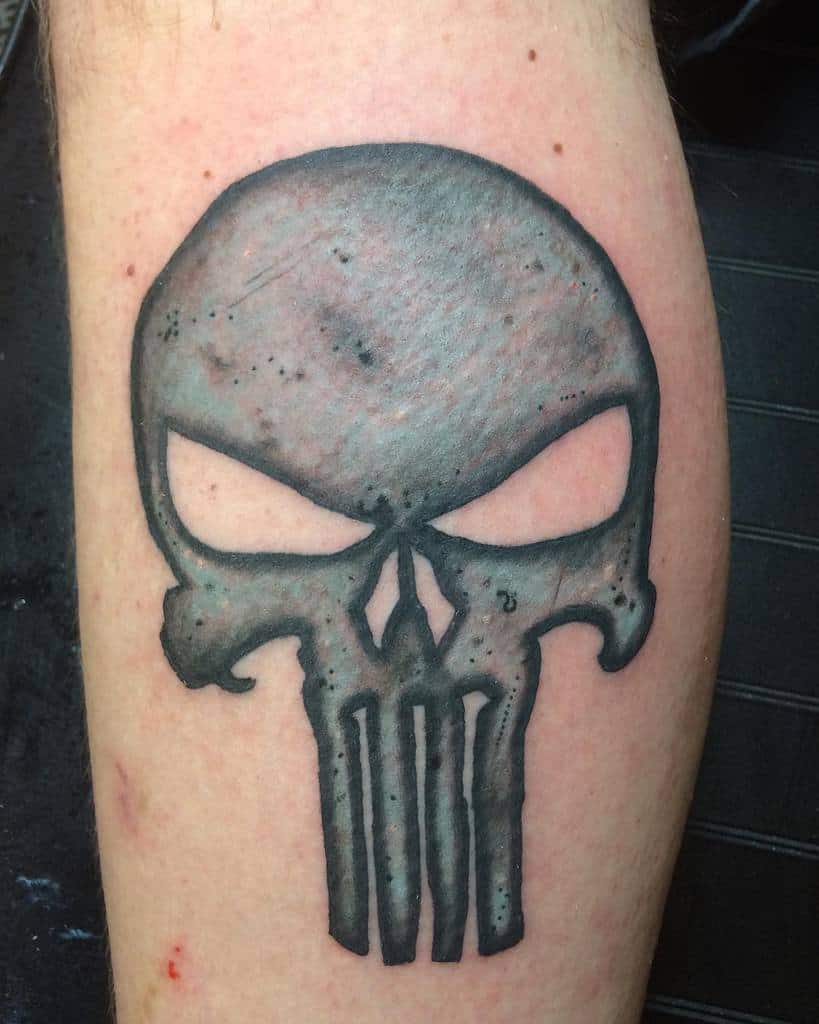 Black and gray Punisher skull tattoo with shading on a leg