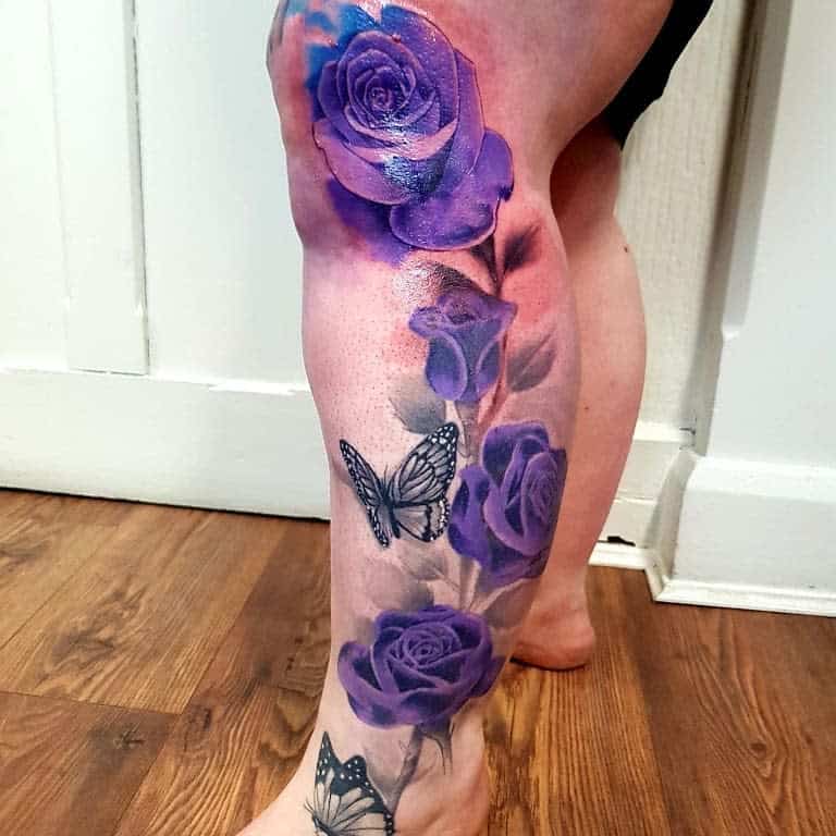 A stunning leg tattoo featuring purple roses and elegant black butterflies