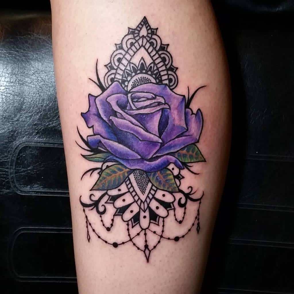 A tattoo of a purple rose with intricate black mandala designs and dangling elements