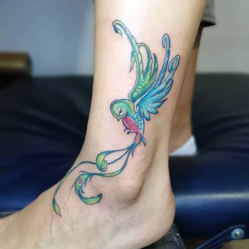 Colorful tattoo of a stylized quetzal with flowing plumage on an ankle
