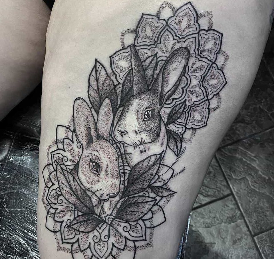 Tattoo of two rabbits with intricate floral and leaf designs