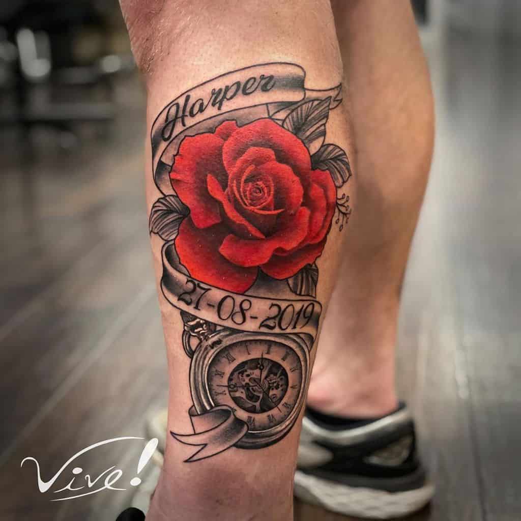 A stunning tattoo on a leg features a vibrant red rose intertwined with a banner bearing meaningful text, all elegantly framed by an intricately detailed pocket watch
