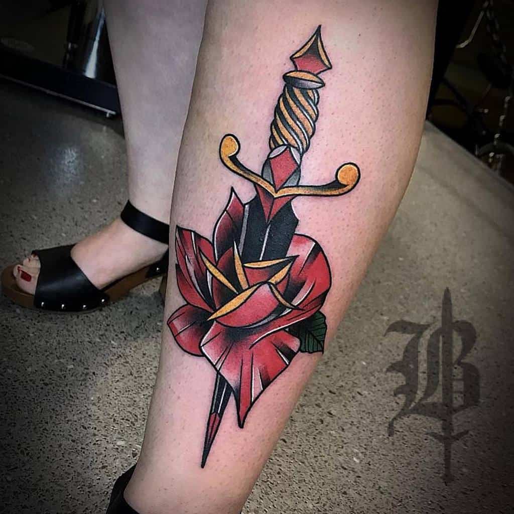 Tattoo of a dagger and rose on a lower leg with a bold design