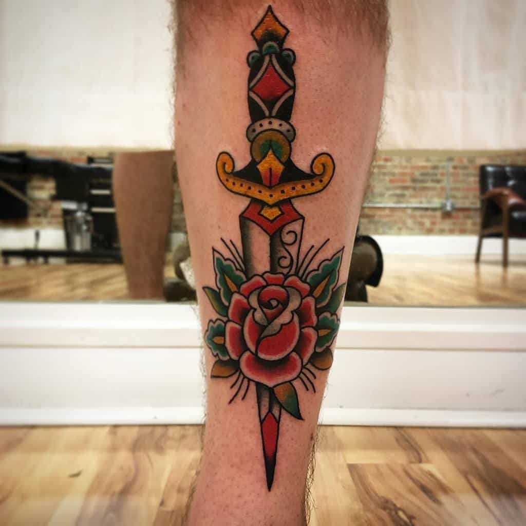 Tattoo of a dagger and rose on a leg