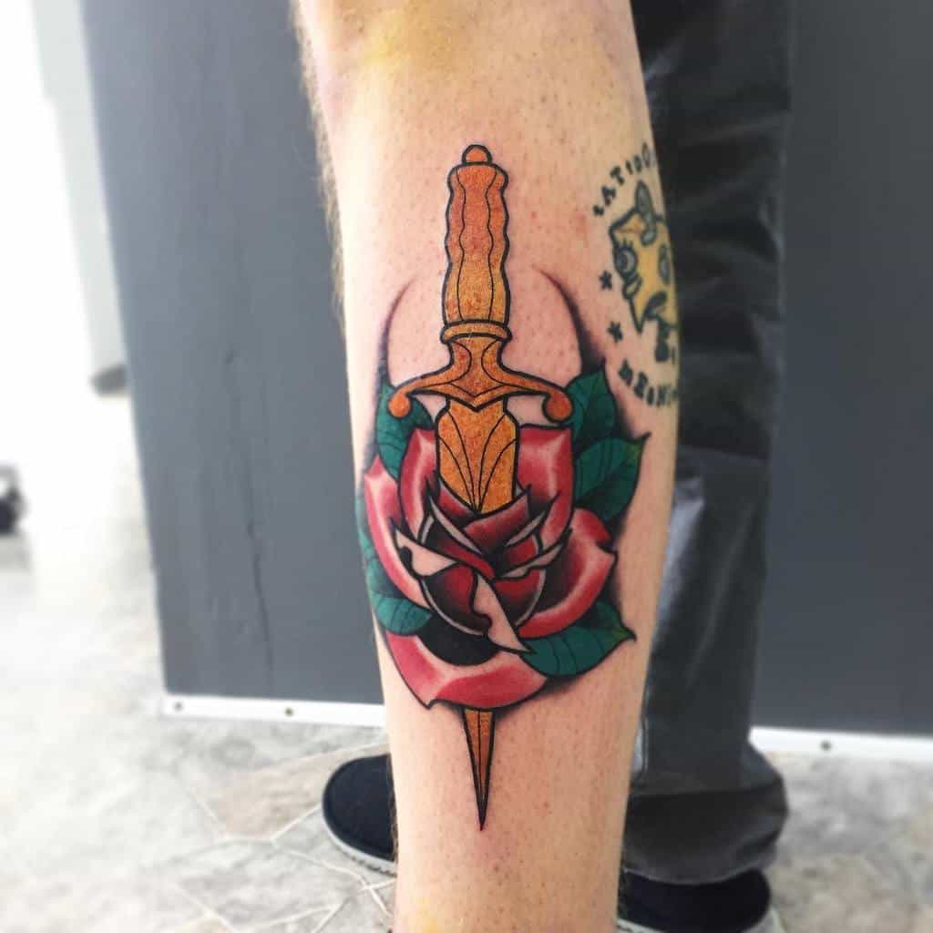 Tattoo of a dagger through a rose on a calf