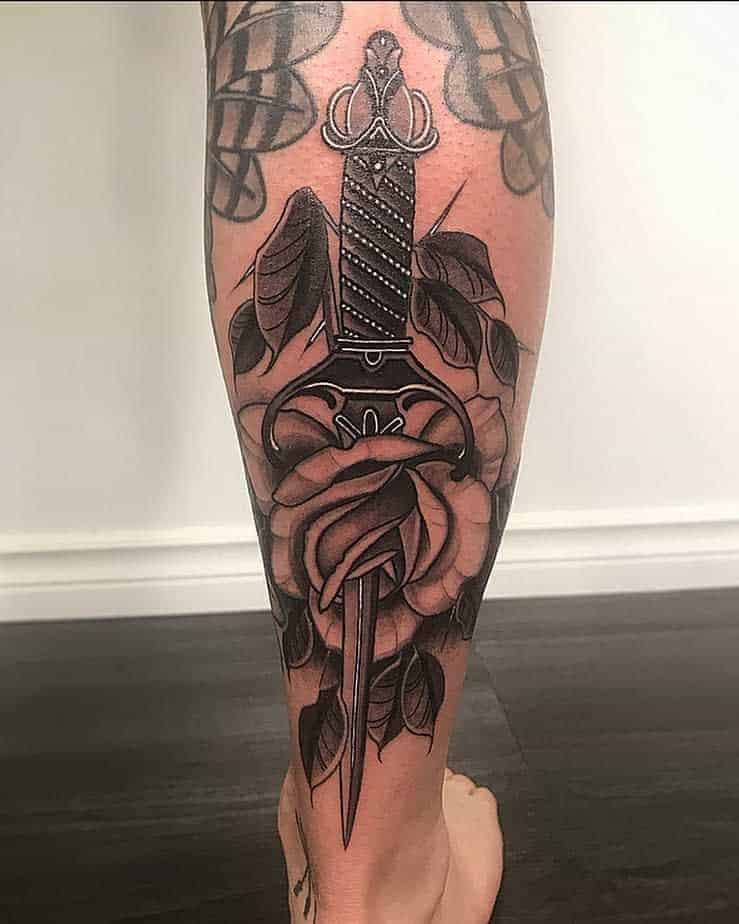 Tattoo of a dagger through a rose on a calf
