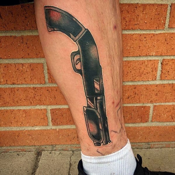 Bold black and grey shotgun tattoo on the leg, featuring a curved grip and shaded detailing for a rugged and powerful design.