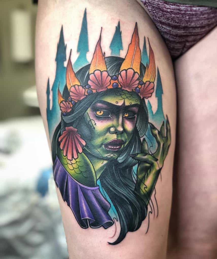 Bold and colorful thigh tattoo of a siren with green skin, a seashell crown, and vibrant forest-inspired background