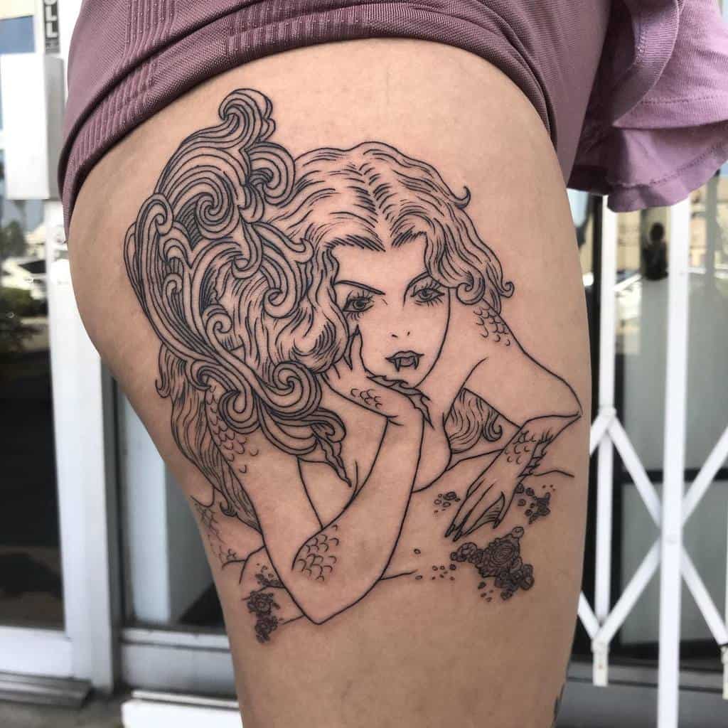 Bold linework tattoo of a seductive siren with wavy hair and intricate scales, resting on the thigh with a mysterious gaze
