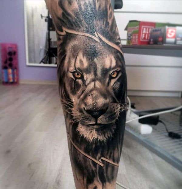 Intricate lion tattoo on a person's leg with a background of barbed wire