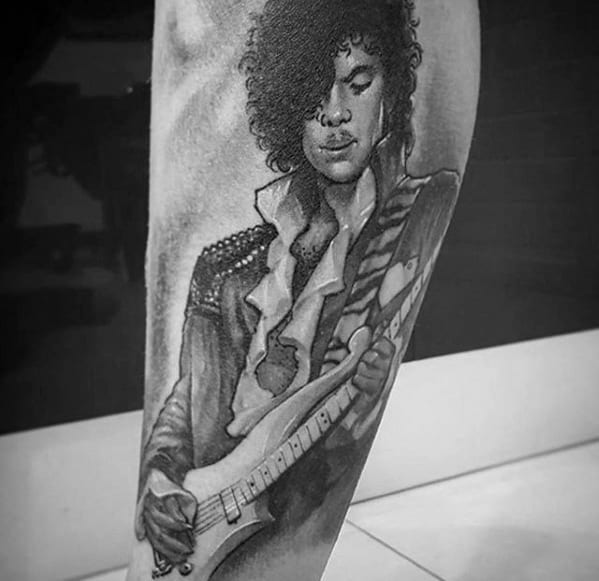 Black and white tattoo of a person with curly hair, playing an electric guitar, in a Prince-inspired outfit