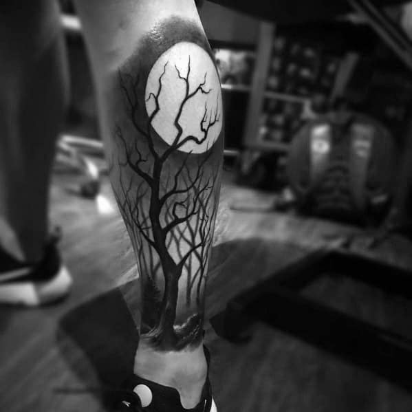 Black and grey tattoo of a leafless tree silhouetted against a glowing full moon, creating a haunting and atmospheric nighttime scene.