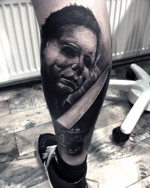 Black and grey Michael Myers tattoo featuring his eerie mask, a reflective knife, and the infamous house for a haunting horror design.