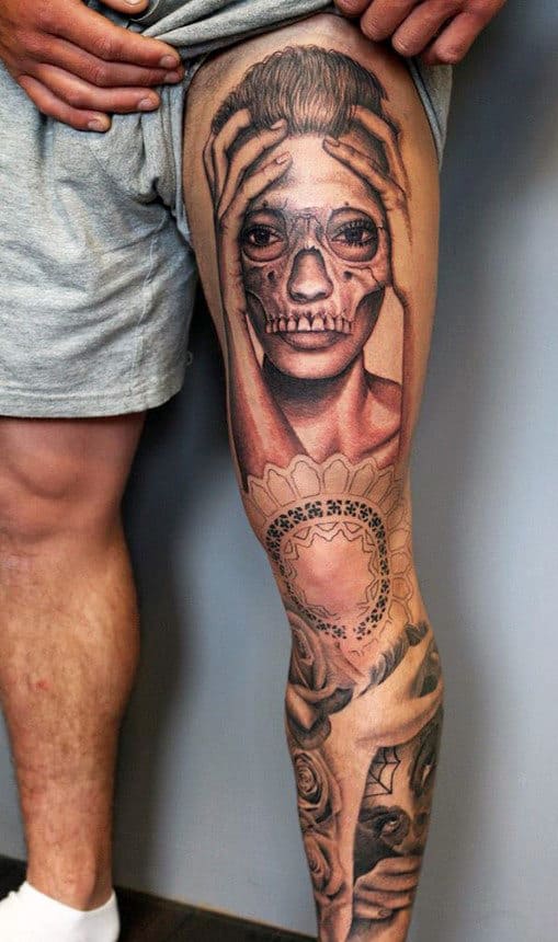 Detailed tattoo of a face with skull makeup on a leg