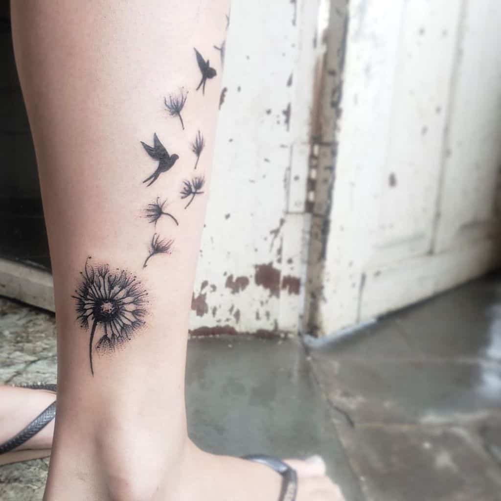 This tattoo showcases a dandelion with its seeds drifting away, transforming into birds, symbolizing freedom and the fleeting nature of life.