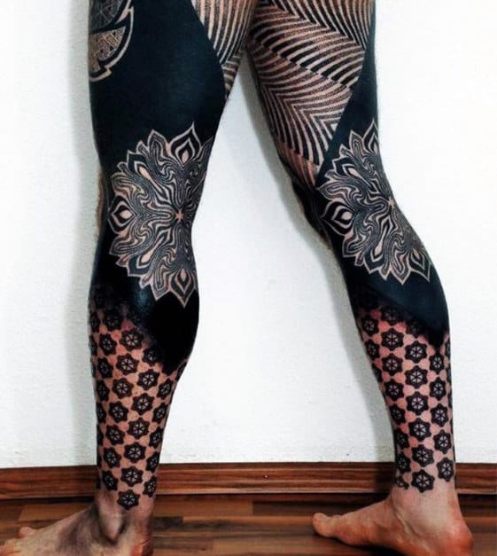 Person with intricate leg tattoos featuring geometric and floral patterns