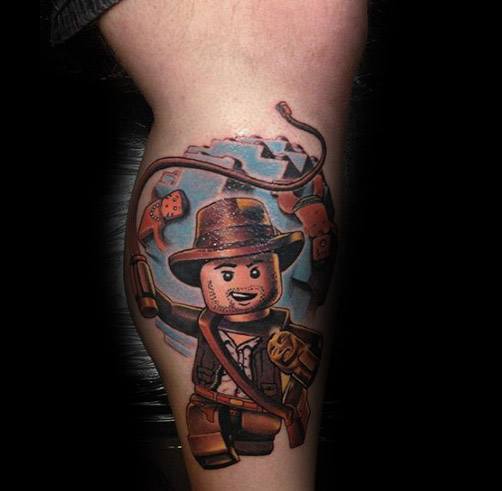Colorful tattoo of LEGO Indiana Jones, featuring his fedora, whip, and adventurous expression with a dynamic background.
