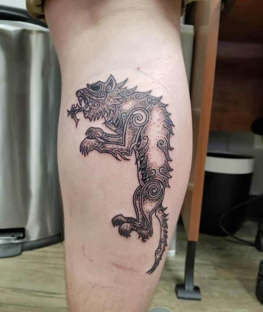 This detailed Norse wolf tattoo, placed on the thigh, is composed of intricate dotwork and bold swirling patterns, embodying strength and ancient mythology