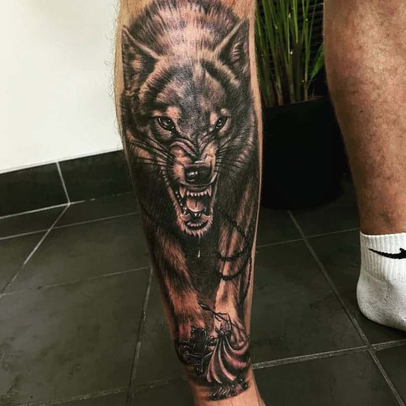 This striking leg tattoo features a hyper-realistic Norse wolf design, showcasing intense details and sharp contrasts that symbolize power and ferocity