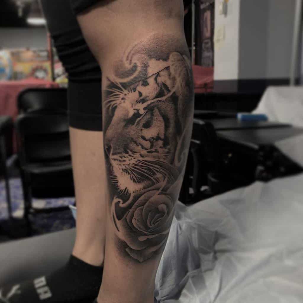 A striking tattoo featuring a majestic lion entwined with a delicate rose adorns the person's leg, exuding an aura of strength and grace reminiscent of a tiger's fierce spirit