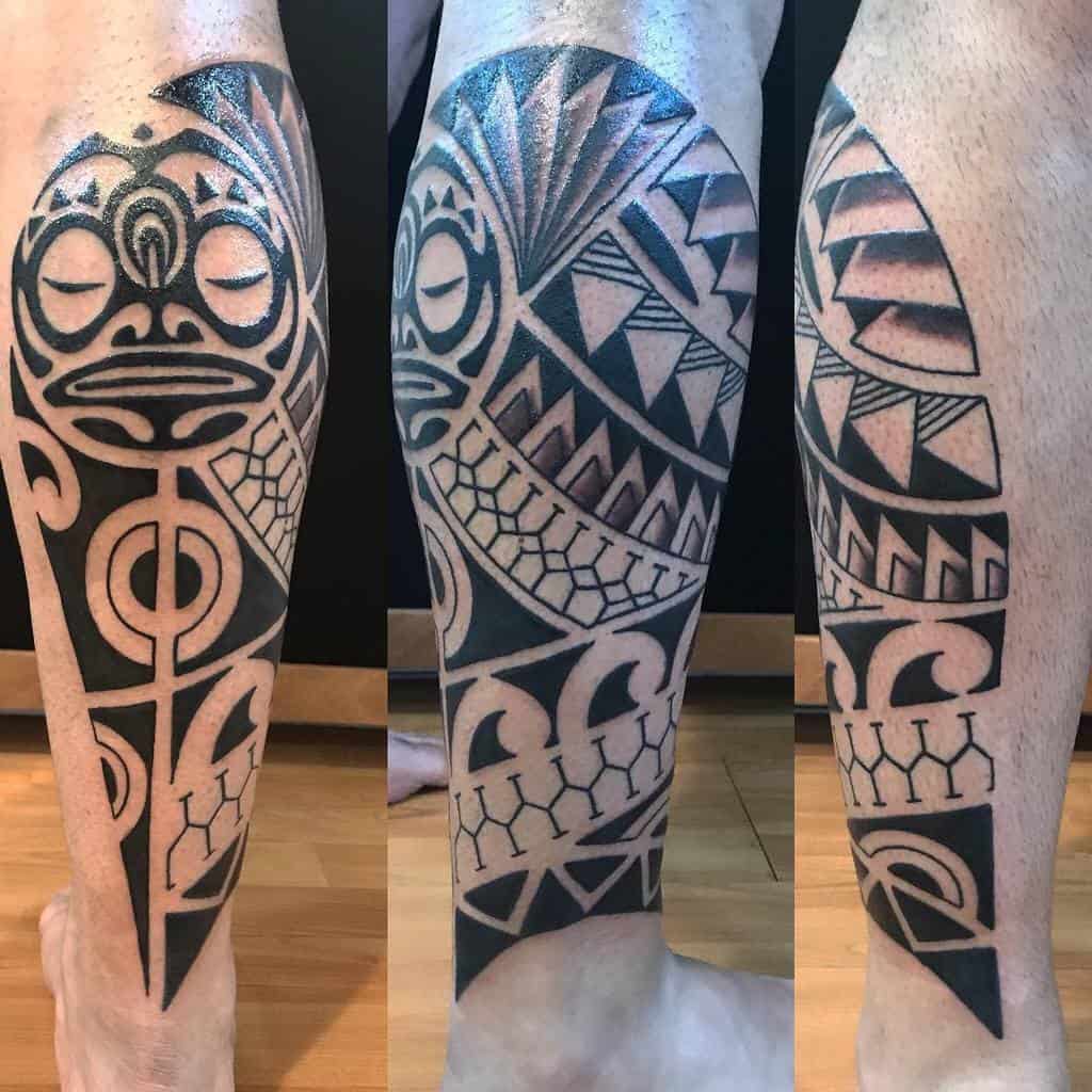 A large black tribal tattoo of a Tiki mask and geometric patterns, the design features bold lines, circles, and sharp angles