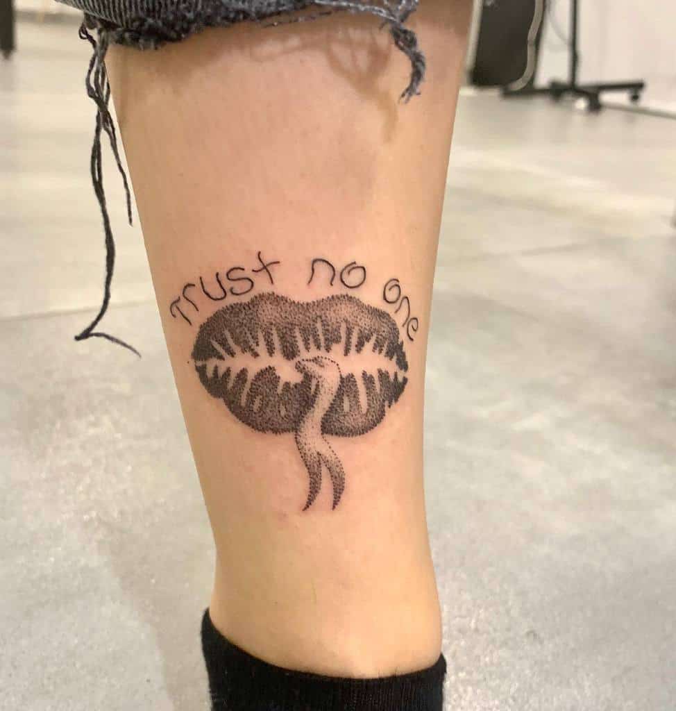 Tattoo of lips, snake's tongoue and "trust no one" on a calf