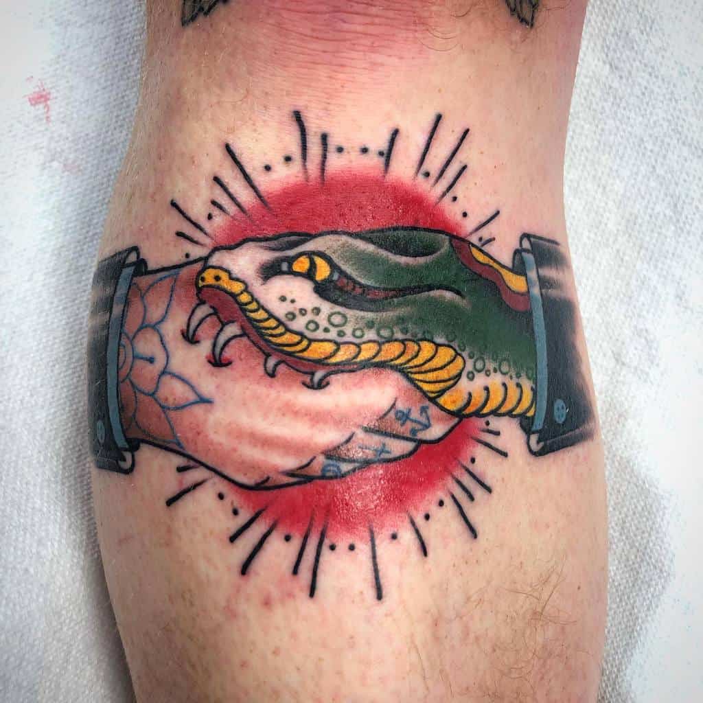 Traditional leg tattoo of a handshake with a green snake, surrounded by a red sunburst and bold, vibrant details