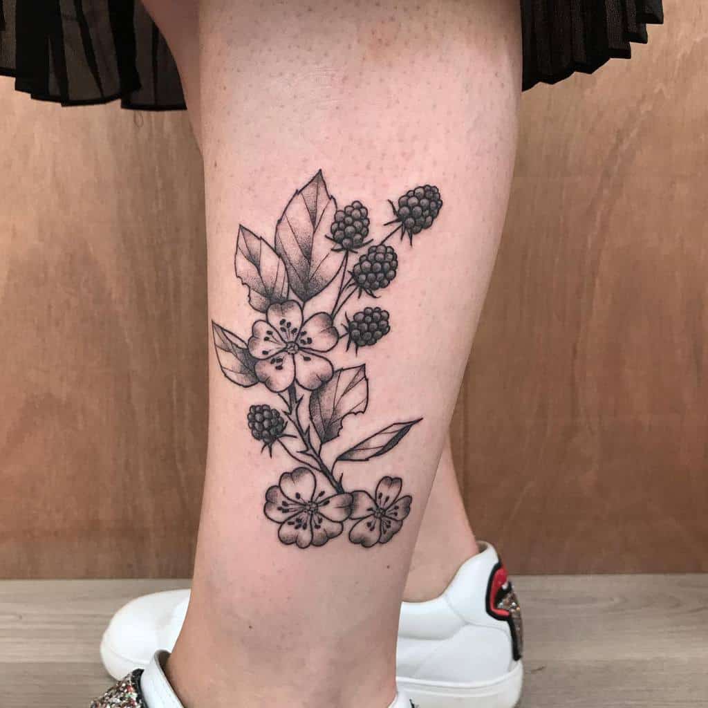Tattoo of flowers and berries on a woman's lower leg