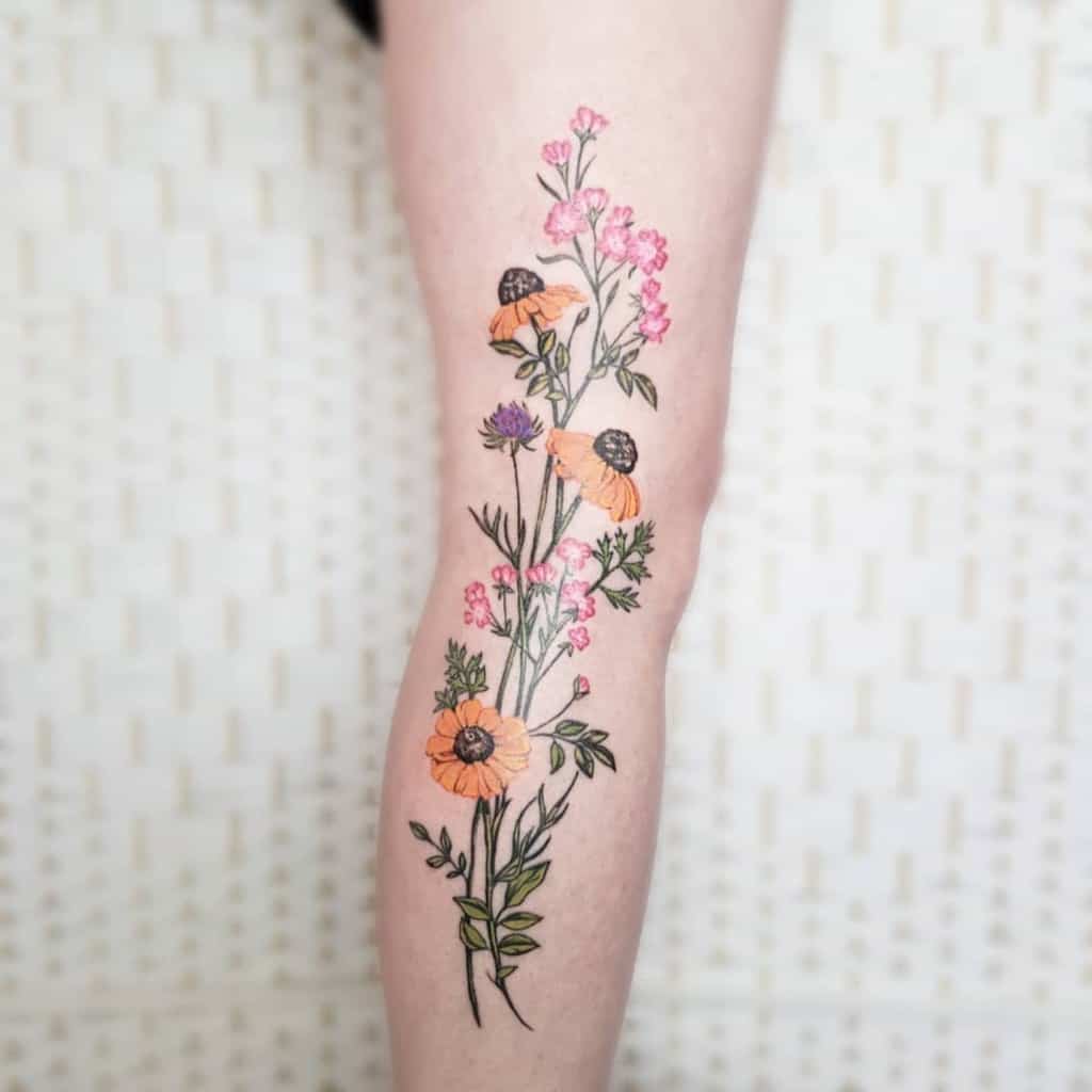 Tattoo of colorful flowers and leaves on a leg