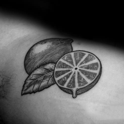 Detailed black ink tattoo of a whole lemon, a sliced half, and a leaf, featuring fine linework and dot shading.
