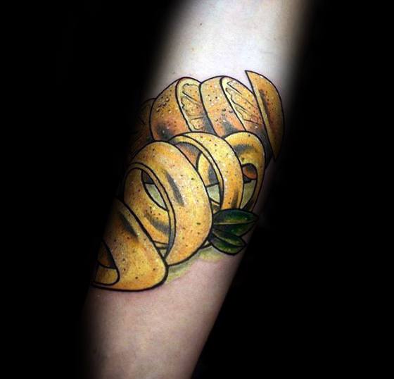 Colorful tattoo of a twisted lemon peel with realistic texture and shading, accented by a small green leaf.