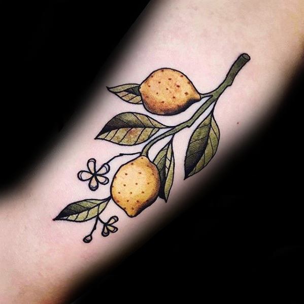 Delicate tattoo of a lemon branch with two lemons, green leaves, and small blossoms, outlined in black with soft shading.