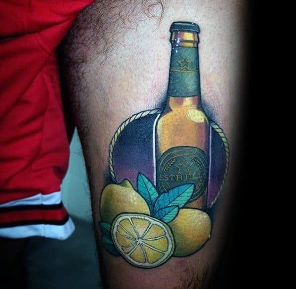 Colorful tattoo of an Estrella beer bottle with whole and sliced lemons, framed by a rope and set against a purple background.