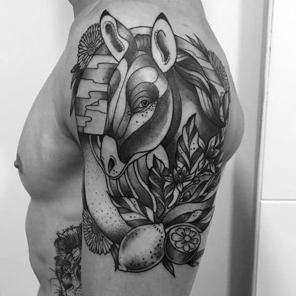 Large black and grey tattoo featuring a stylized zebra head surrounded by lemons, flowers, and foliage with detailed shading and patterns.