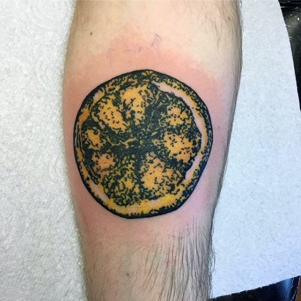 Tattoo of a lemon slice with a textured, mold-like effect in dark green and yellow, creating a unique, grungy appearance.