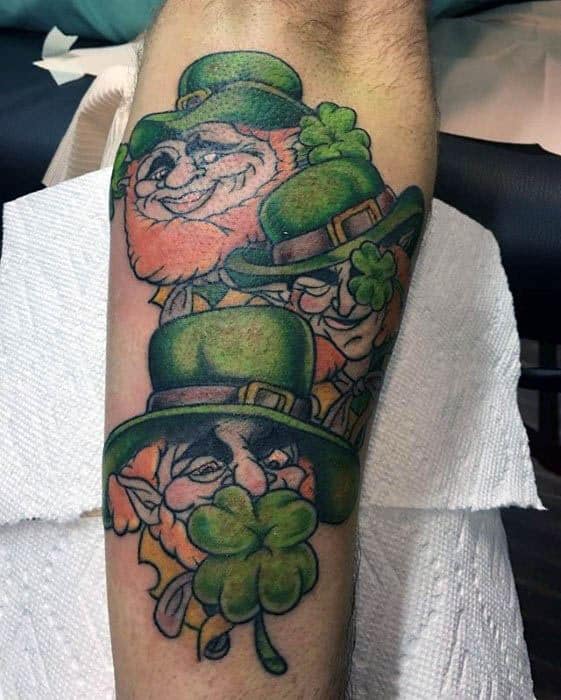 Leprechaun tattoo featuring three whimsical faces in green hats, each holding a shamrock with bold outlines and vibrant colors.