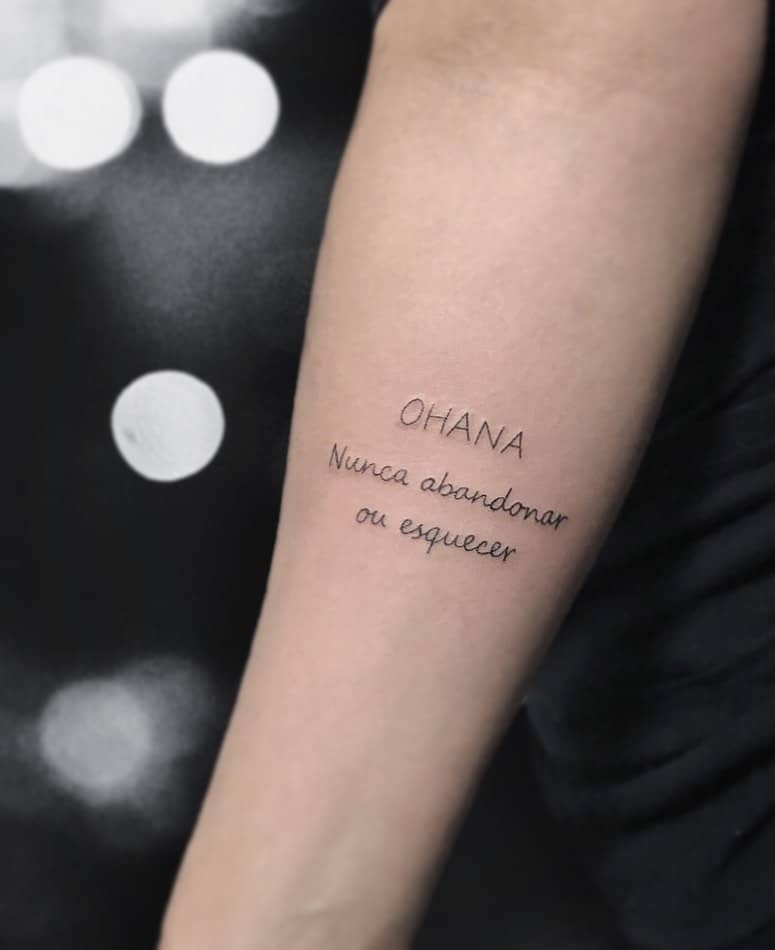 Simple tattoo with 'Ohana' and the phrase 'Nunca abandonar ou esquecer' (Never abandon or forget), symbolizing family loyalty and connection.