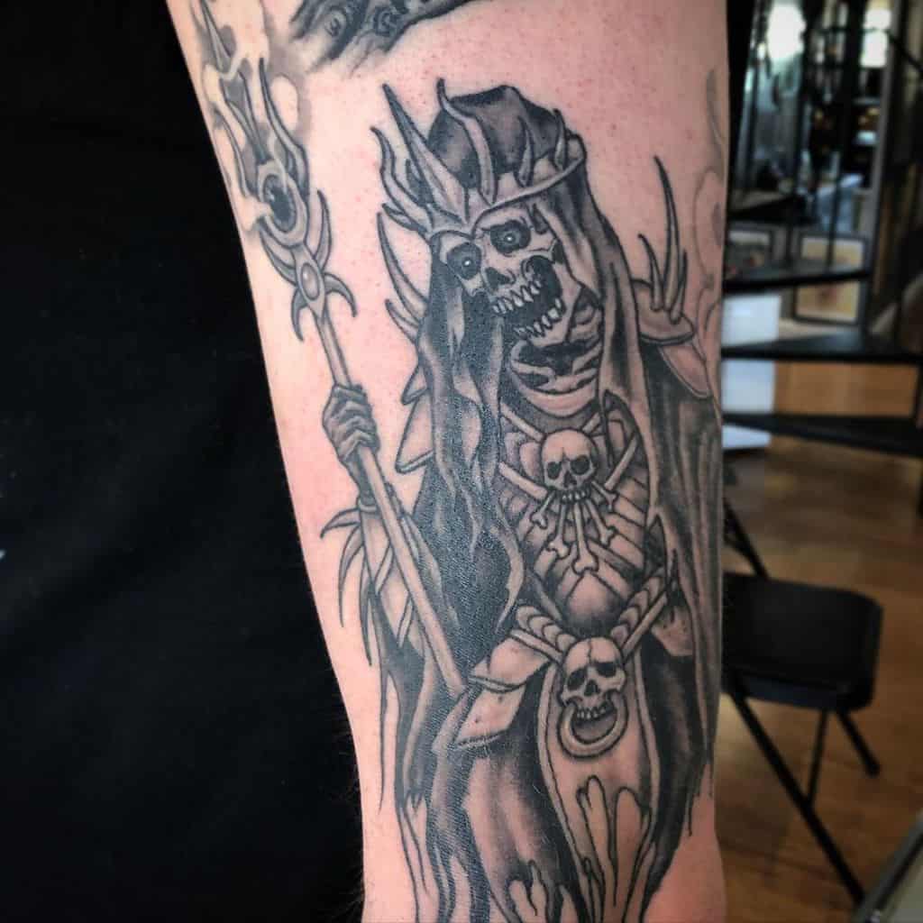 Skeleton sorcerer tattoo, detailed with skull motifs and holding a mystical staff, evoking dark fantasy themes