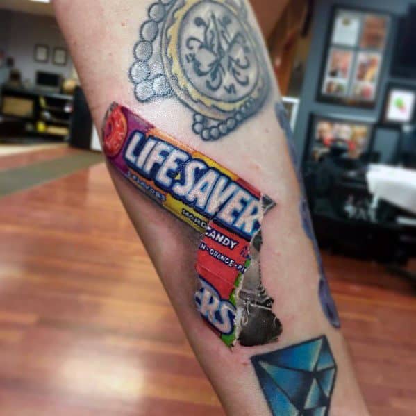 Realistic Life Savers candy tattoo with a torn wrapper effect, showcasing vibrant colors and intricate shading for a striking 3D appearance.