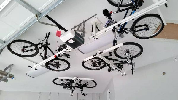 Garage with multiple bikes stored on ceiling-mounted lift racks for space-saving storage.