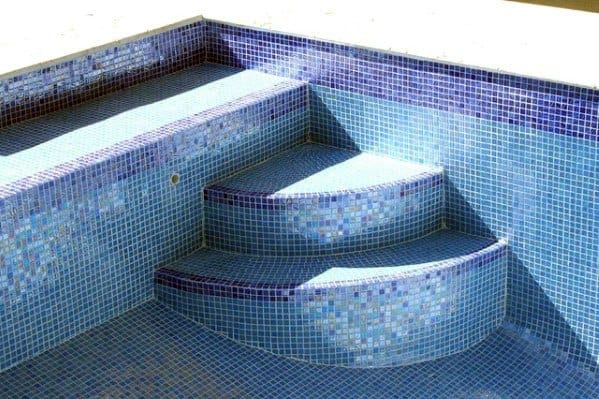 Rounded pool steps with light blue and navy mosaic tiles, creating a clean and elegant design.