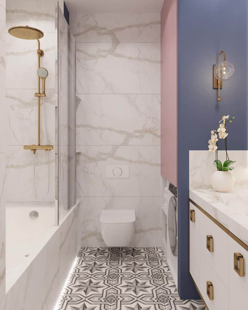 Small bathroom with marble shower, patterned tile floor, and blue and pink cabinetry with laundry.