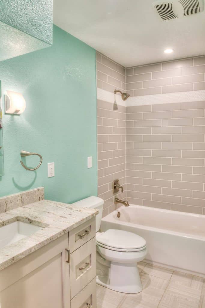 pale blue accent wall in gray tile bathroom 