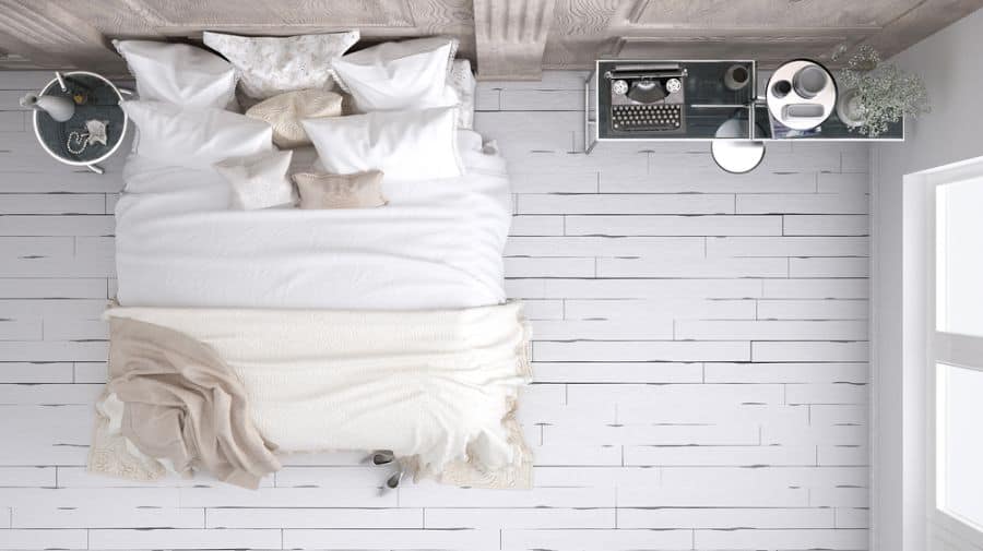 Overhead view of a cozy bedroom featuring a king bed, typewriter, and light-colored flooring.