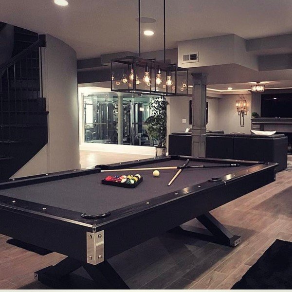 Modern basement with black pool table, glass pendant lights, and open living area.