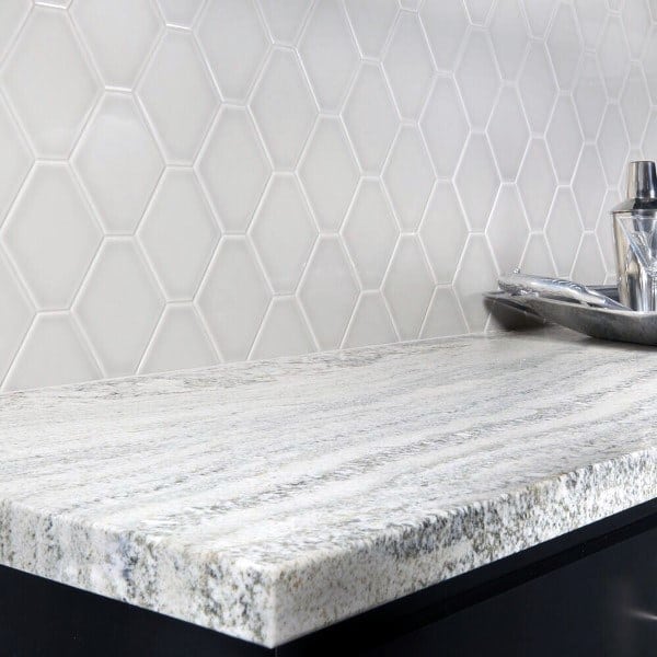Textured gray countertop with light gray hexagon tile backsplash and white grout.