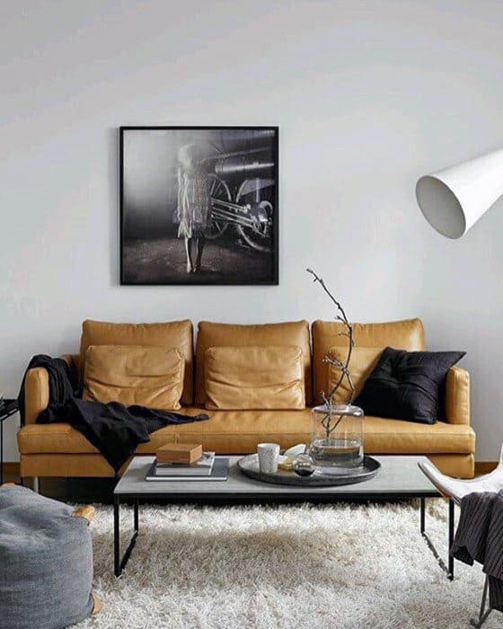 Cozy living room with a tan leather sofa, black coffee table, and soft white shag area rug.