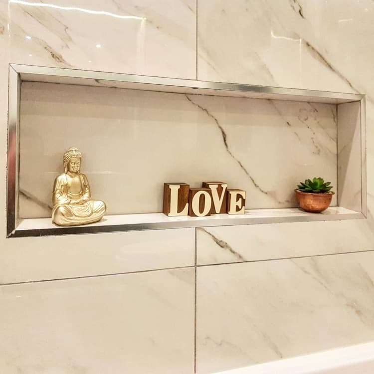 Recessed marble shelf with Buddha statue, "Love" sign, and small potted plant.