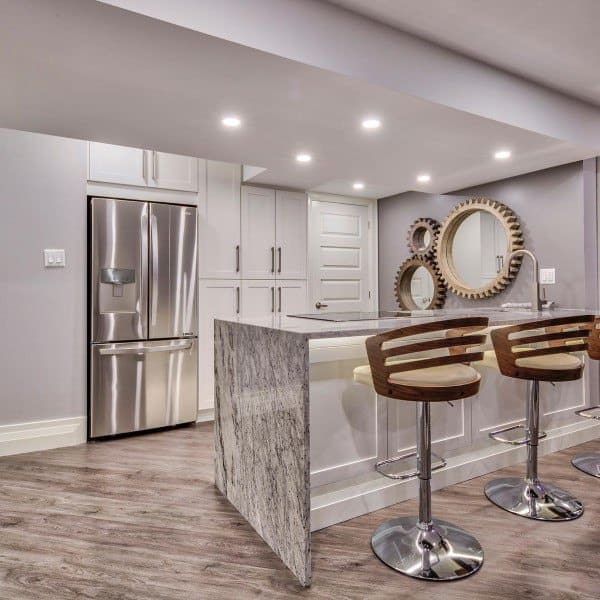 Modern basement kitchen with marble island, bar stools, and recessed lighting.
